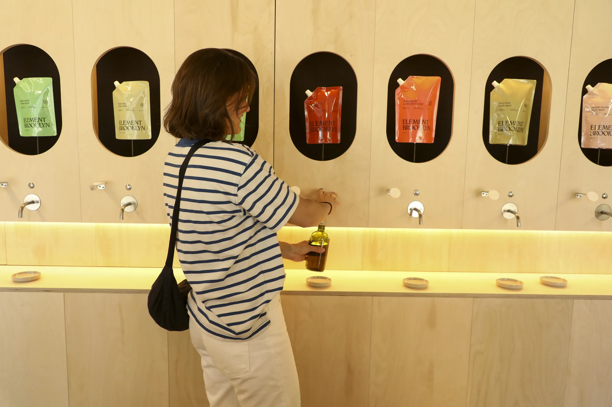 A visitor refilling a bottle at the Element Brooklyn refill wall