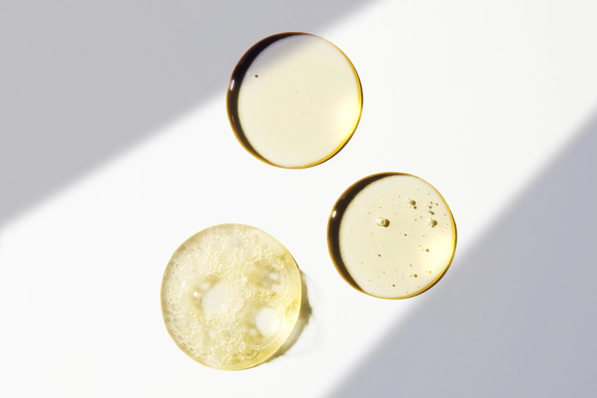 Drops of clear golden liquid soap on a white surface